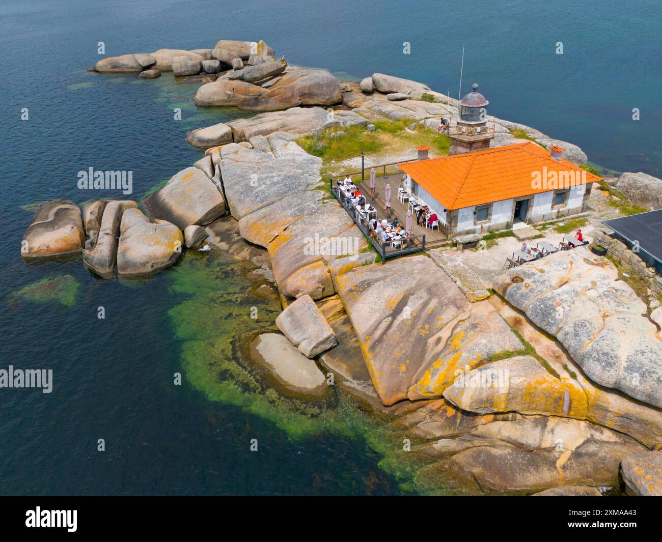 Un phare sur une île rocheuse, entouré d'eau claire, avec un toit de couleur orange et un petit bâtiment, vue aérienne, A Illa de Arousa, la Isla Banque D'Images