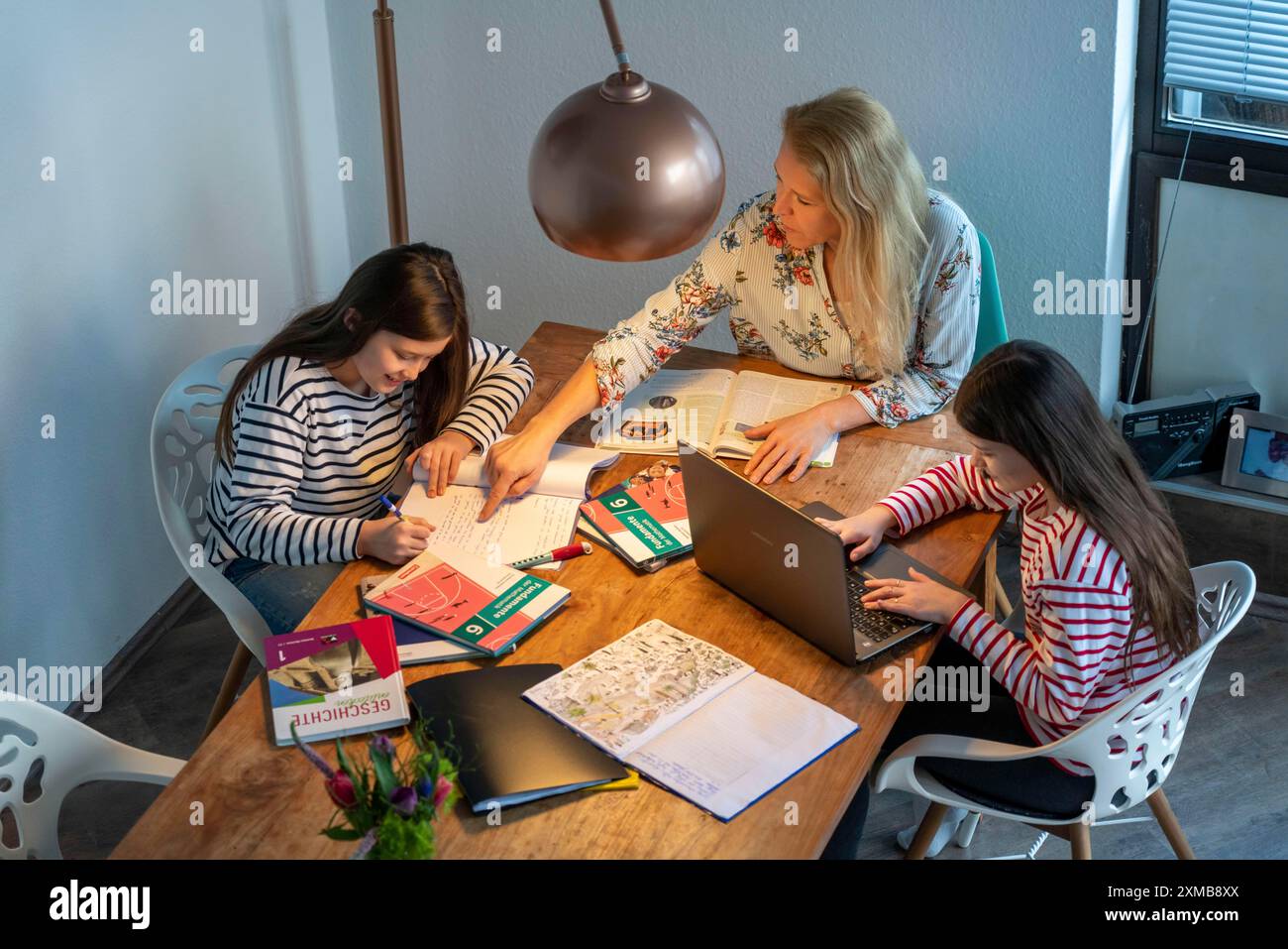 Homeschooling, pendant le confinement en janvier 2021, mère aide ses deux filles, à la maison, à apprendre, avec des manuels et des ordinateurs, des fermetures d'écoles Banque D'Images