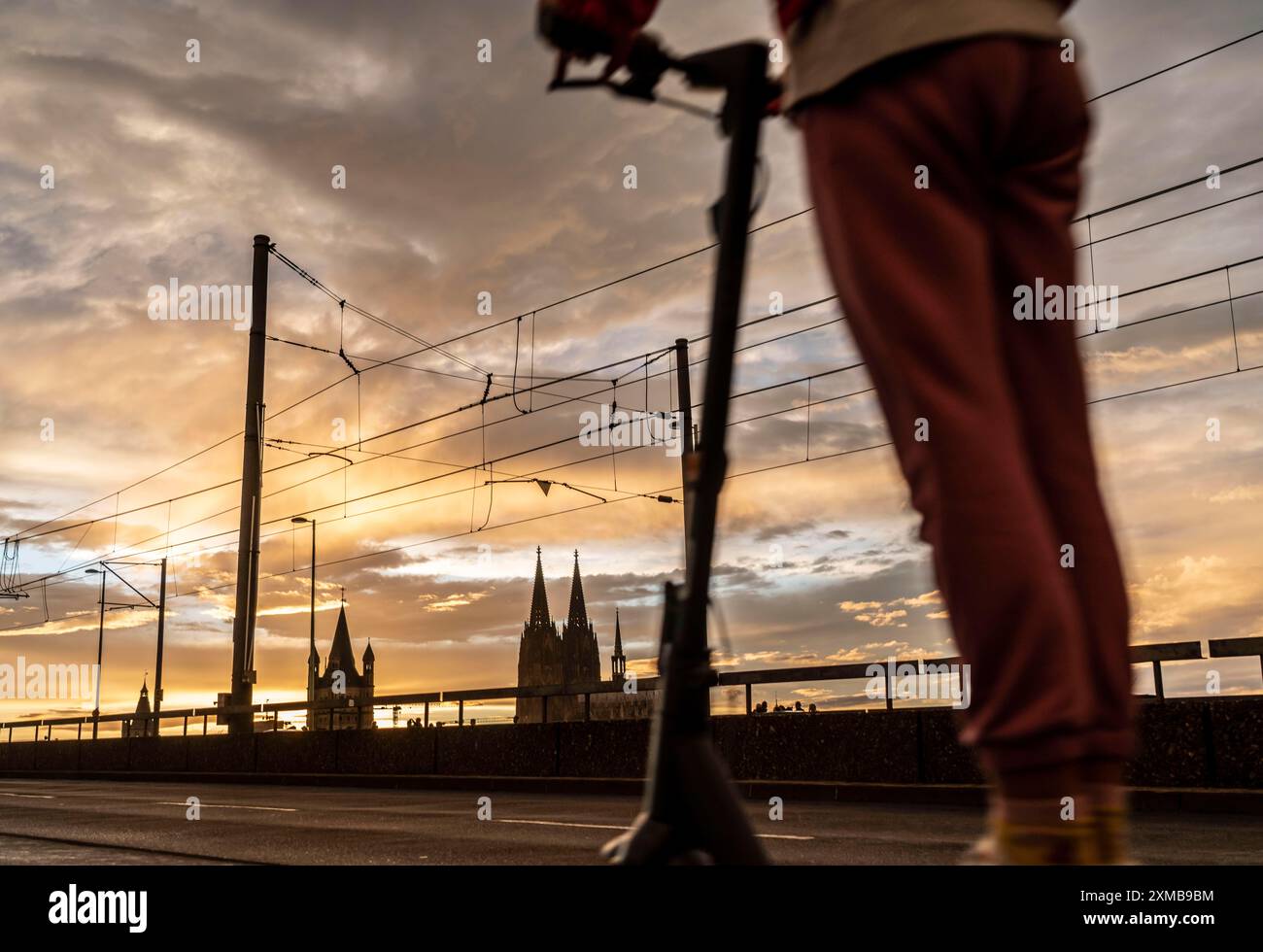 Skyline avec cathédrale de Cologne, Gross créé Martin Catholic Church, Deutz Bridge, Sunset, e-scooter driver, Cologne, Rhénanie du Nord-Westphalie, Allemagne Banque D'Images