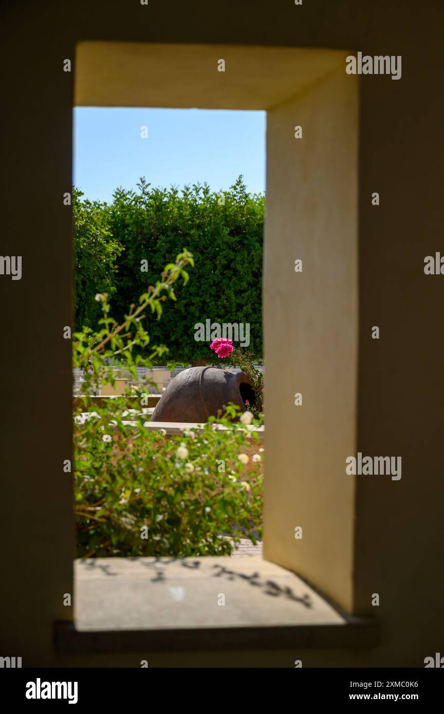 Une fenêtre de jardin donnant sur un jardin luxuriant avec des fleurs et un grand pot. Le bâtiment Luxury Aphrodite Hills Hotel and Resort avec de beaux jardins Banque D'Images