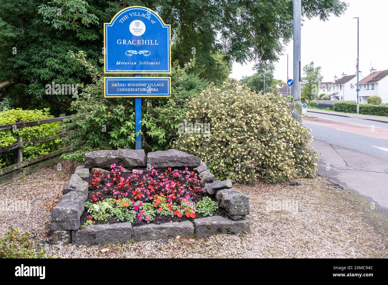 Gracehill, Irlande du Nord - 26 juillet 2024 : la colonie historique de l'église morave remporte le statut de patrimoine mondial de l'UNESCO, signe bleu du village et fleurs. Banque D'Images