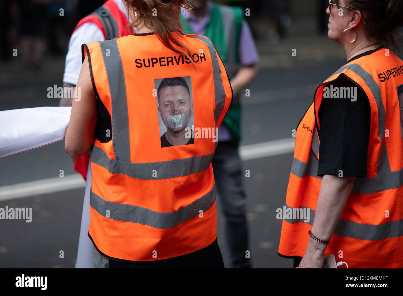 Londres, Royaume-Uni. 27 juillet 2024. Steward portant une veste avec le visage de Tommy Robinson avec du ruban adhésif sur sa bouche pendant le rallye. Les partisans de l’ex-dirigeant de l’EDL (Ligue de défense anglaise) et fondateur Tommy Robinson, de son vrai nom Stephen Christopher Yaxley-Lennon, ont défilé vers Trafalgar Square pour manifester contre ce qu’ils appellent un « système de police à deux vitesses », l’immigration et le mouvement LGBTQ. Une contre-manifestation a également été organisée par divers groupes. Crédit : SOPA images Limited/Alamy Live News Banque D'Images