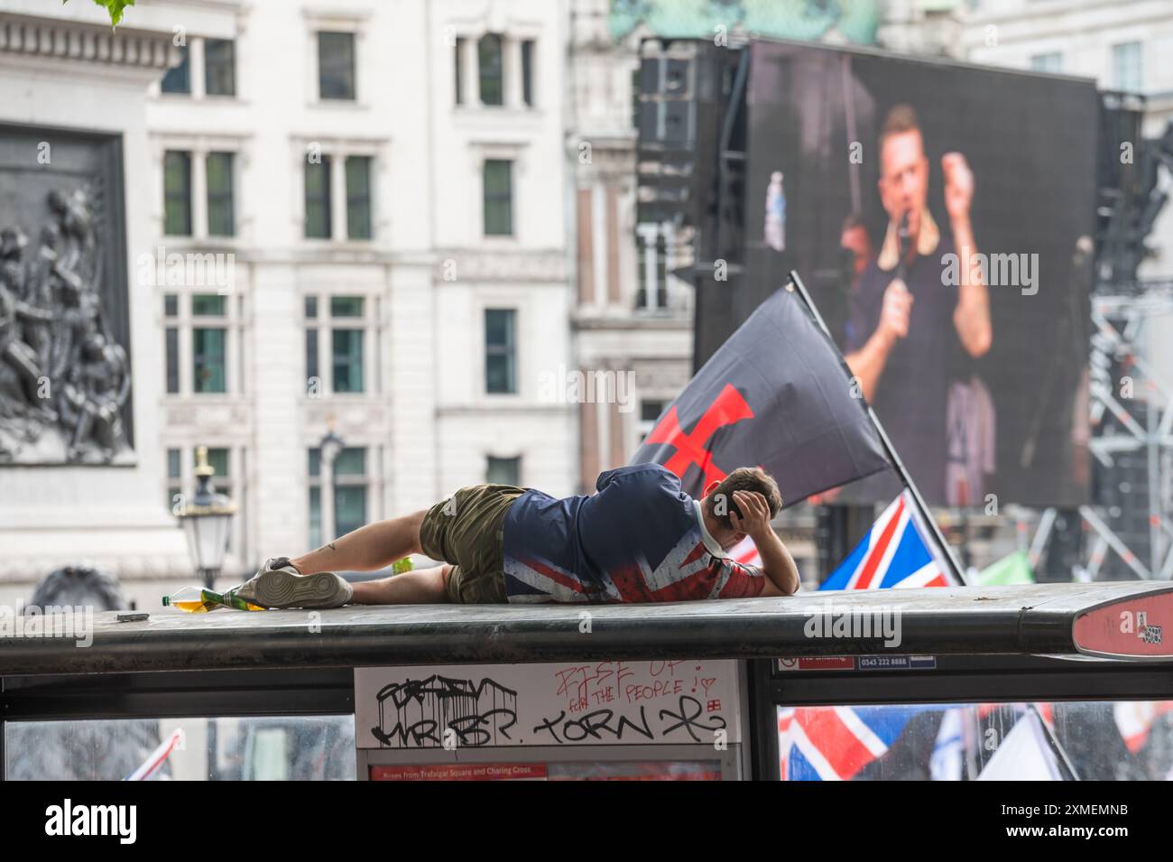 Londres, Royaume-Uni. 27 juillet 2024. Un partisan de Tommy Robinson vu au sommet d'un arrêt de bus alors qu'il assistait au rassemblement à Trafalgar Square. Les partisans de l’ex-dirigeant de l’EDL (Ligue de défense anglaise) et fondateur Tommy Robinson, de son vrai nom Stephen Christopher Yaxley-Lennon, ont défilé vers Trafalgar Square pour manifester contre ce qu’ils appellent un « système de police à deux vitesses », l’immigration et le mouvement LGBTQ. Une contre-manifestation a également été organisée par divers groupes. Crédit : SOPA images Limited/Alamy Live News Banque D'Images