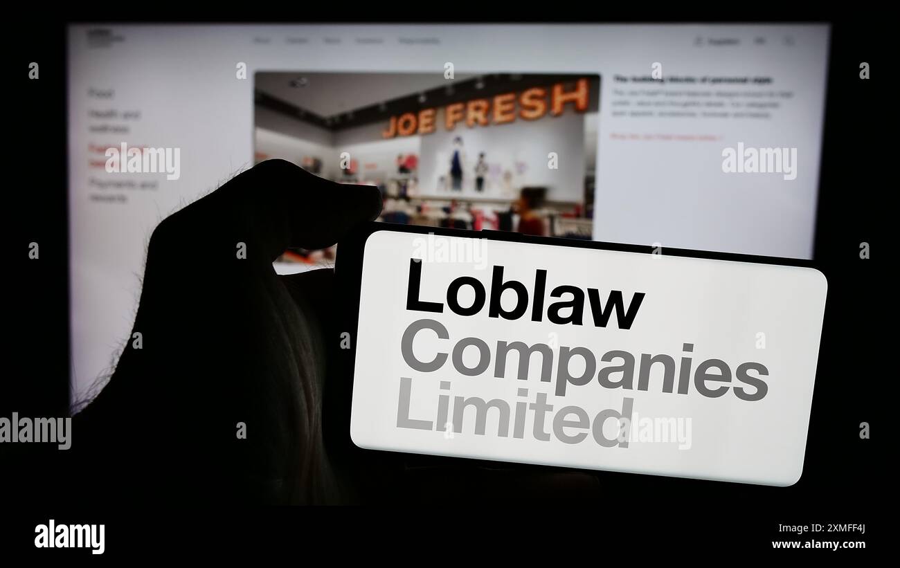 Personne tenant un téléphone intelligent avec le logo de la société canadienne de vente au détail Loblaw Companies Ltd. Devant le site Web. Concentrez-vous sur l'affichage du téléphone. Banque D'Images