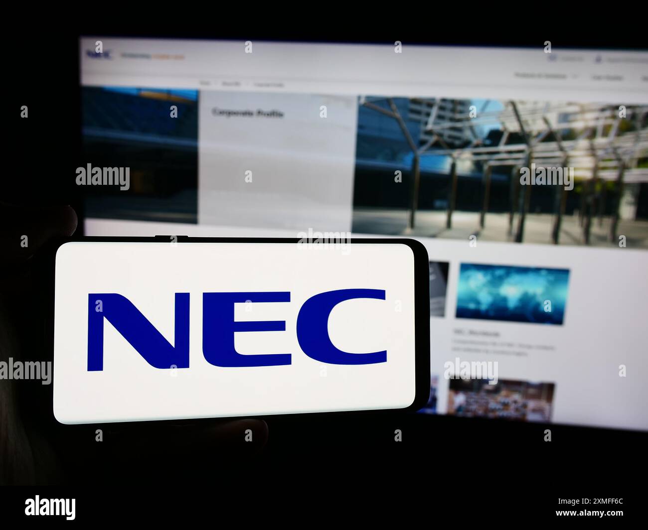 Personne tenant un smartphone avec le logo de la société japonaise de technologie de l'information NEC Corporation en face du site Web. Concentrez-vous sur l'affichage du téléphone. Banque D'Images