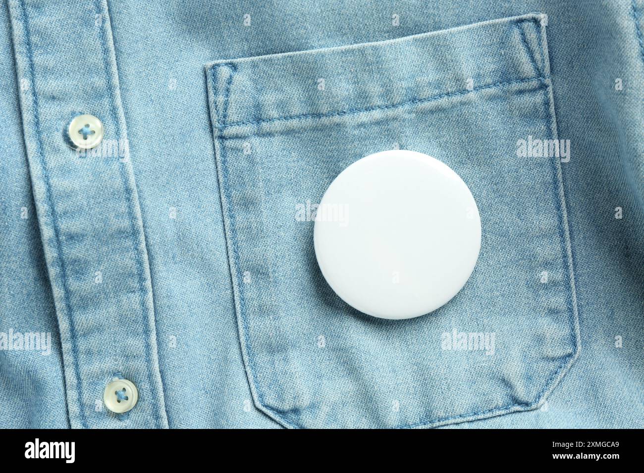 Badge bouton blanc épinglé sur la chemise en Jean, vue de dessus. Maquette pour le design Banque D'Images