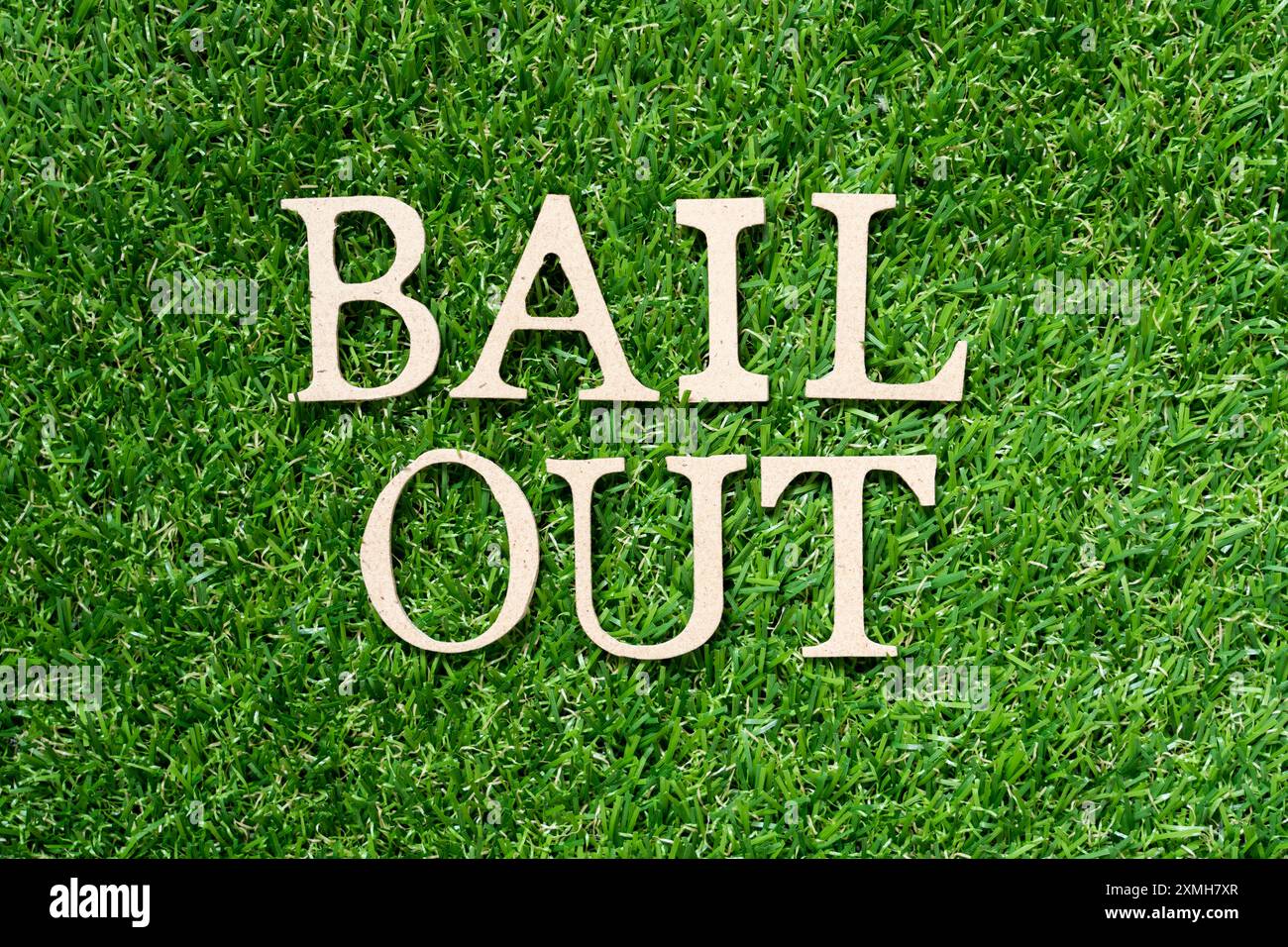 Lettre de l'alphabet en bois dans le mot bail out sur fond d'herbe verte artificielle Banque D'Images