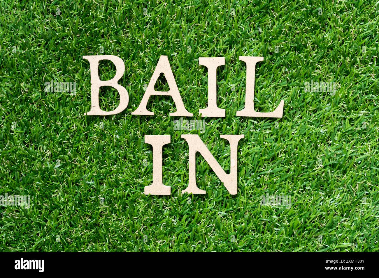 Lettre de l'alphabet en bois dans le mot bail in sur fond d'herbe verte artificielle Banque D'Images