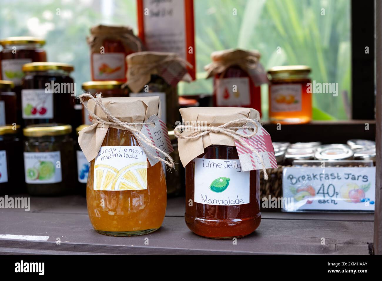 Une petite exposition de confitures, marmelades et chutneys faits maison dans un cabinet à l'extérieur d'un chalet. les bocaux ont des étiquettes écrites à la main qui incluent un prix Banque D'Images