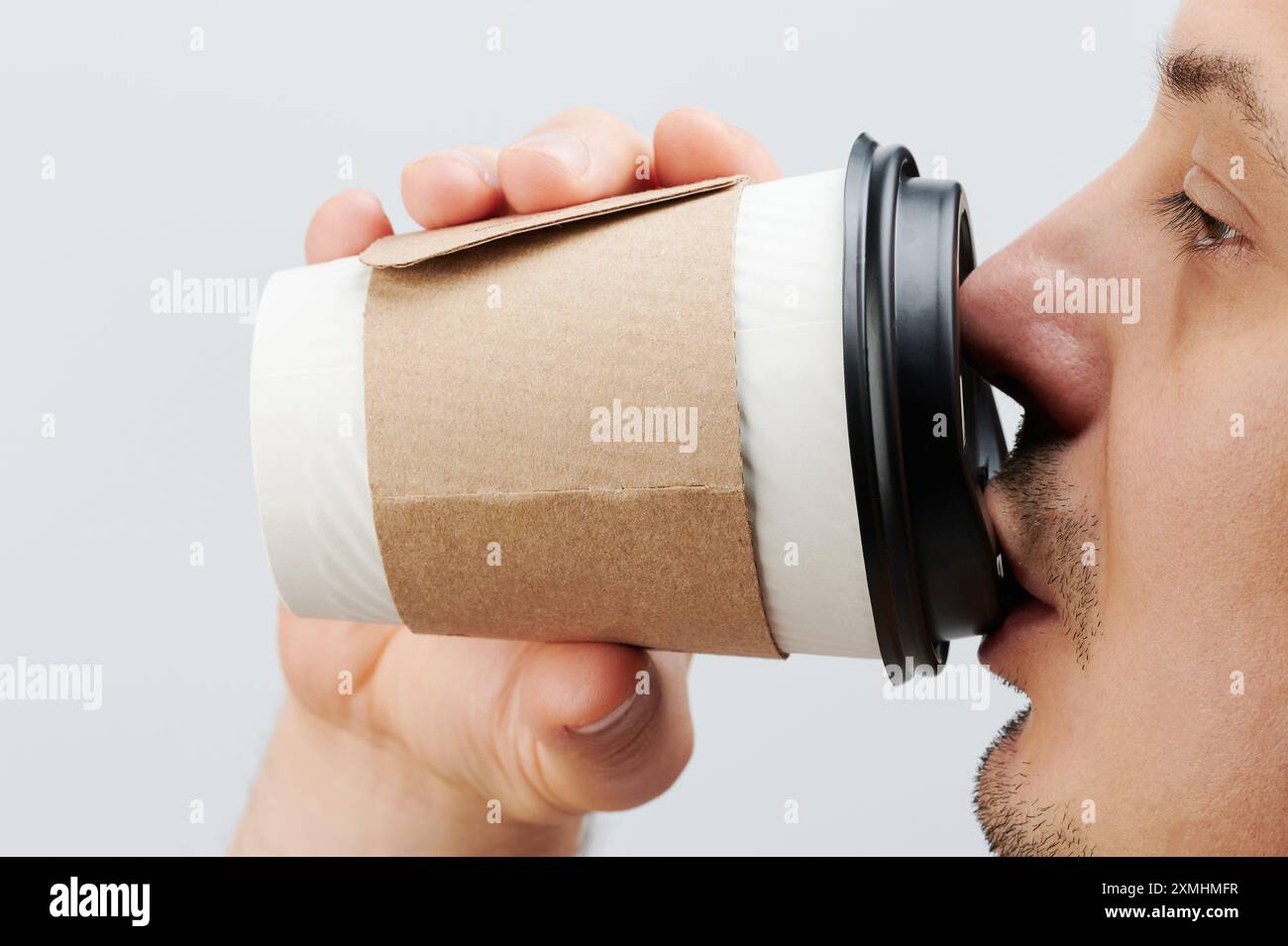 Gros plan de gars buvant de tasse de papier isolé sur fond blanc de studio Banque D'Images