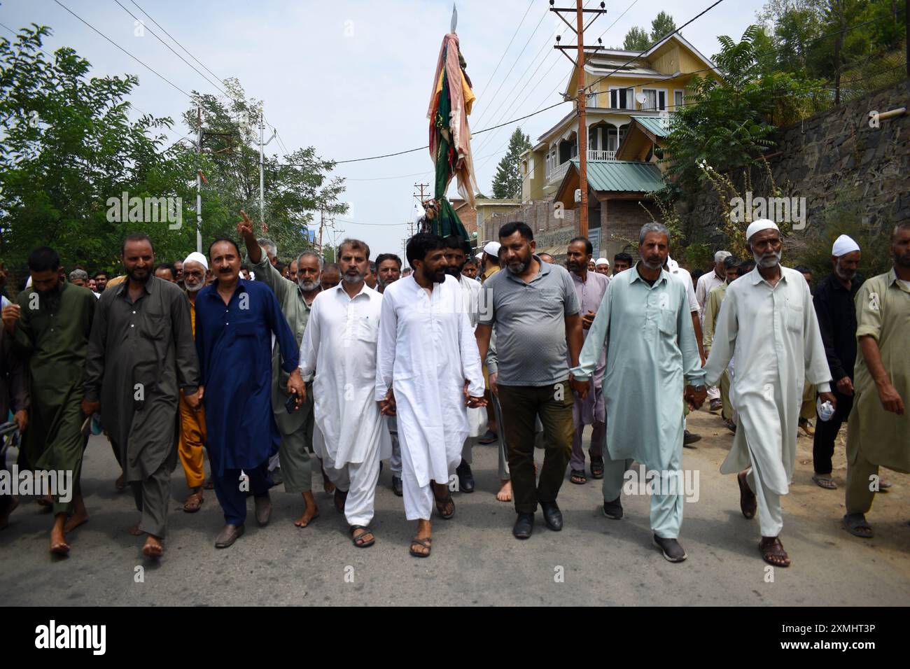 Srinagar, Cachemire, Inde, le 28 juillet 2024 : un groupe de personnes, marchant pieds nus le long de la route et tenant un Alam, se dirige vers le sanctuaire Sheikh-ul-Alam au Cachemire. Ils prient pour la pluie pour soulager la vague de chaleur qui affecte actuellement la région. Chaque fois que le Cachemire connaît une catastrophe, les groupes se rendent au sanctuaire de Chari Sharief, situé à 28 kilomètres de Srinagar, où le cheikh Noor DIN (R.. A) le sanctuaire est situé. Ces groupes font le voyage à pied, pieds nus, interprétant le traditionnel Band Pather et priant pour ceux qui sont touchés par la catastrophe pendant qu'ils marchent. Photo danoise Showkat/Sipa USA. Banque D'Images