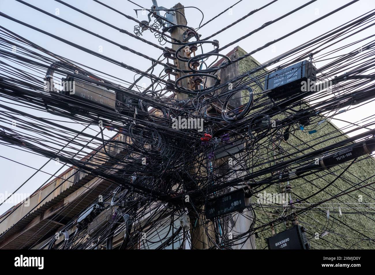 Enchevêtrement sauvage de lignes électriques et de télécommunications sur un poteau de service à Bangkok, Thaïlande. Banque D'Images