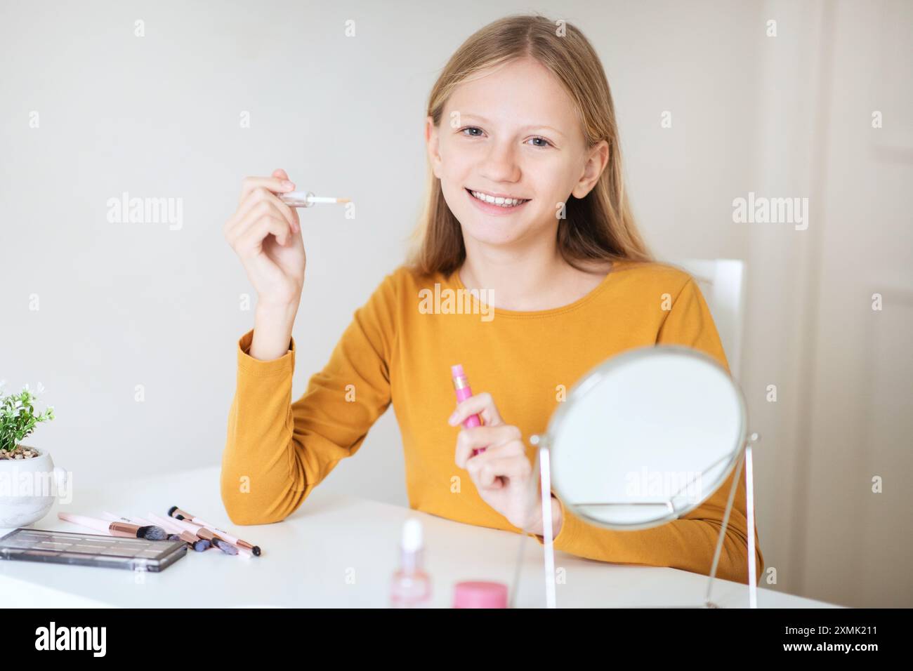 Adolescente appliquant le brillant à lèvres tout en regardant dans un miroir Banque D'Images