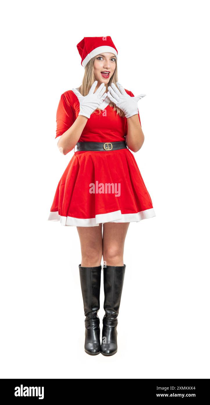 jeune femme latine blonde habillée en costume de père noël pleine longueur regardant la caméra étonnée sur fond blanc Banque D'Images