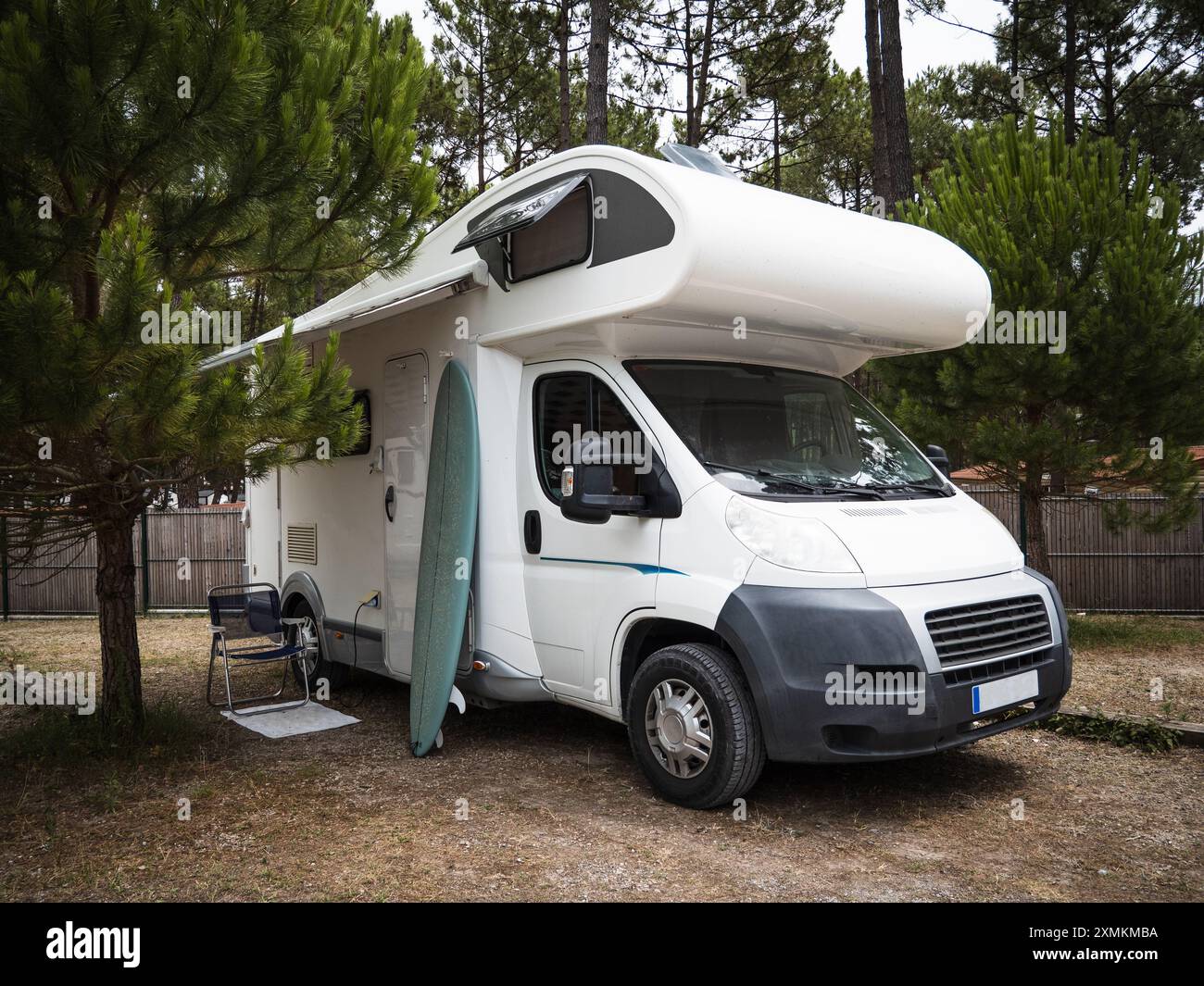 Camping-car garé dans le camping et une chaise et une planche de surf à l'extérieur Banque D'Images