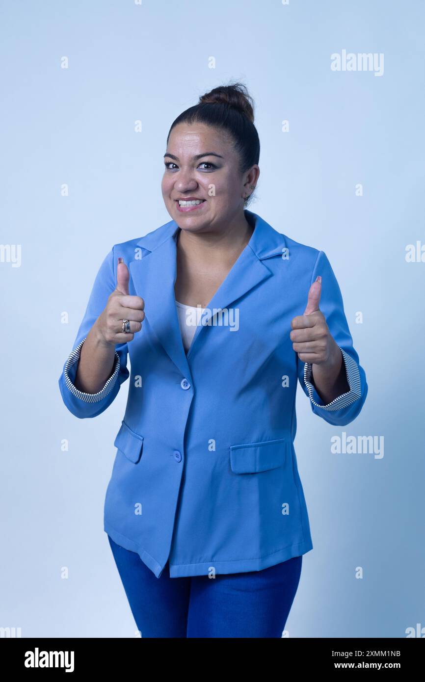 Une femme confiante et positive sourit brillamment tout en donnant un pouce vers le haut, mettant en valeur son professionnalisme et son enthousiasme Banque D'Images