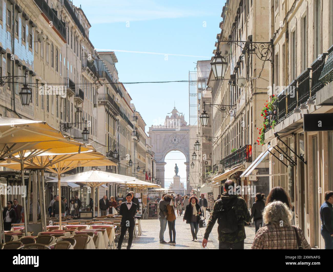 Rue européenne animée avec des cafés, des gens et une arche historique Banque D'Images