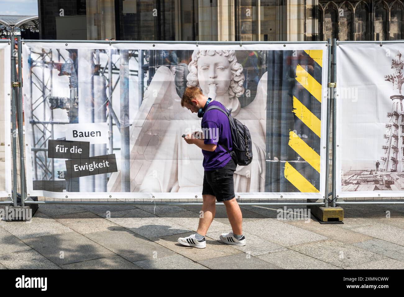 Homme devant une clôture de chantier à la cathédrale, image d'une figure de façade de la cathédrale, Cologne, Allemagne. ***USAGE ÉDITORIAL EXCLUSIF*** MAN Banque D'Images