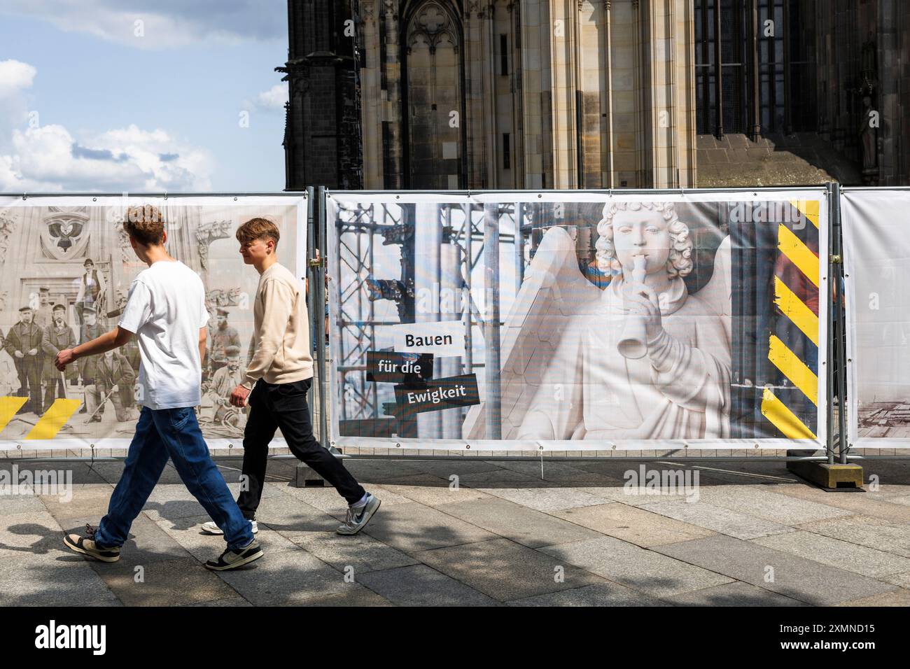 Les gens passent une clôture de chantier en face de la cathédrale, image d'une figure de façade de la cathédrale, Cologne, Allemagne. ***USAGE ÉDITORIAL SEULEMENT*** Banque D'Images