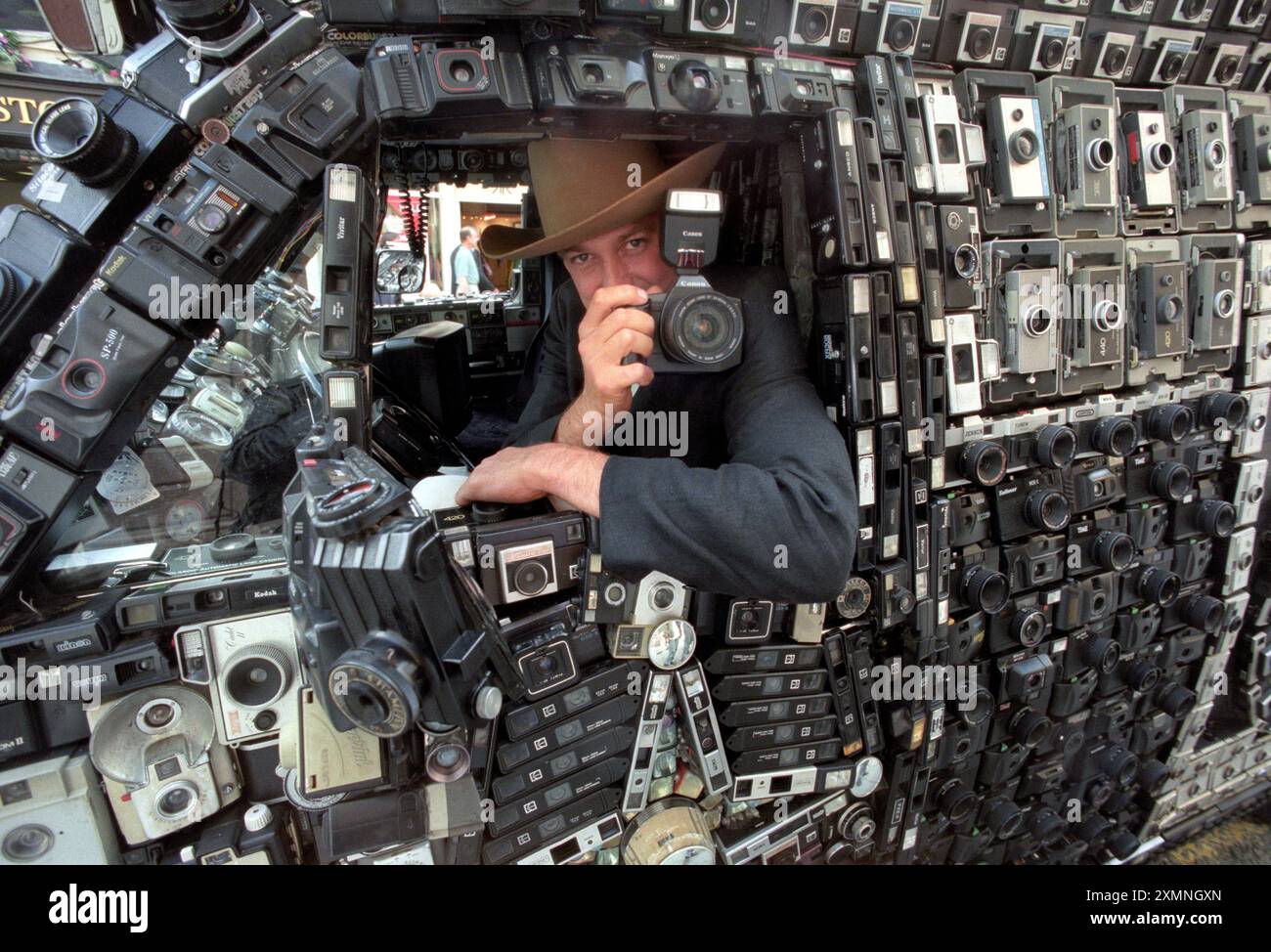 Harrod Blank, un documentariste américain et artiste automobile basé en Californie dans sa camionnette Dodge de 1972 couverte de 1 705 caméras. Il était au Royaume-Uni avec son Camera Van (10 des caméras fonctionnaient - filmant les réactions des gens qui voyaient le véhicule) et ici il est photographié à Bath alors qu'il prenait des photos pour une exposition dans la galerie Drive Thru à Londres plus tard en 1998. Photo de Roger Bamber Banque D'Images