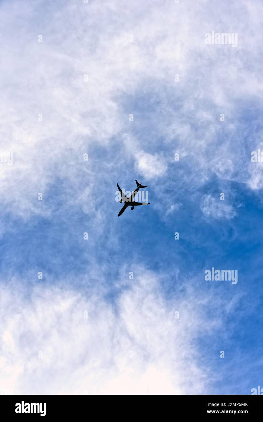 Formes abstraites formées par des nuages de cirrus contre un ciel bleu avec la silhouette d'un jet passager dans le ciel Banque D'Images