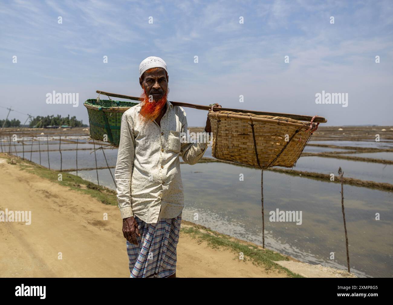 Homme bangladais ramassant du sel dans des paniers, Division de Chittagong, Maheshkhali, Bangladesh Banque D'Images