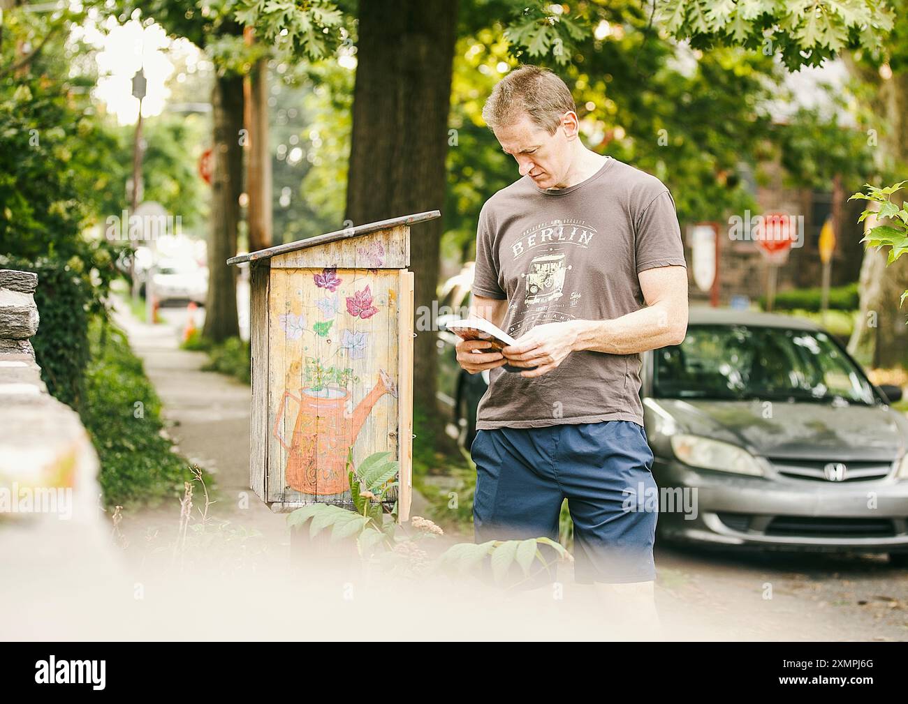 Germantown, Philadelphie, États-Unis, 29 juillet 2024. Un homme regarde la boîte à livres extérieure de la bibliothèque Ilyapa Banque D'Images