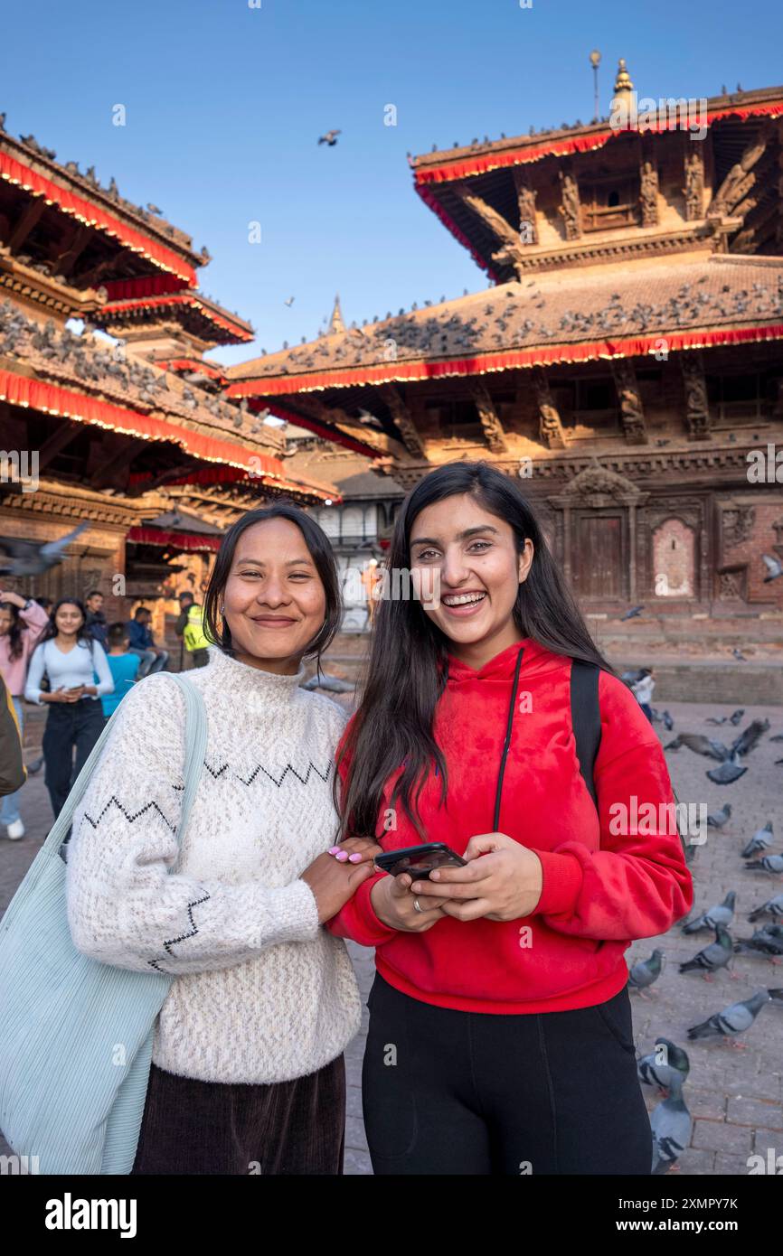 Alors que les corbeaux volent au sujet de jeunes femmes, des amies posent pour le portrait sur la place historique de Drubar, Katmandou, Népal Banque D'Images