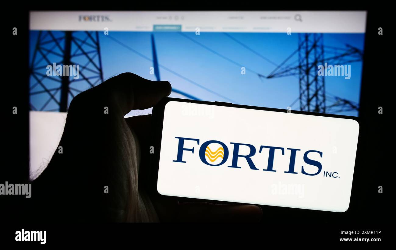 Personne tenant un téléphone mobile avec le logo de la compagnie canadienne de services publics d'électricité Fortis Inc devant la page Web de l'entreprise. Concentrez-vous sur l'affichage du téléphone. Banque D'Images