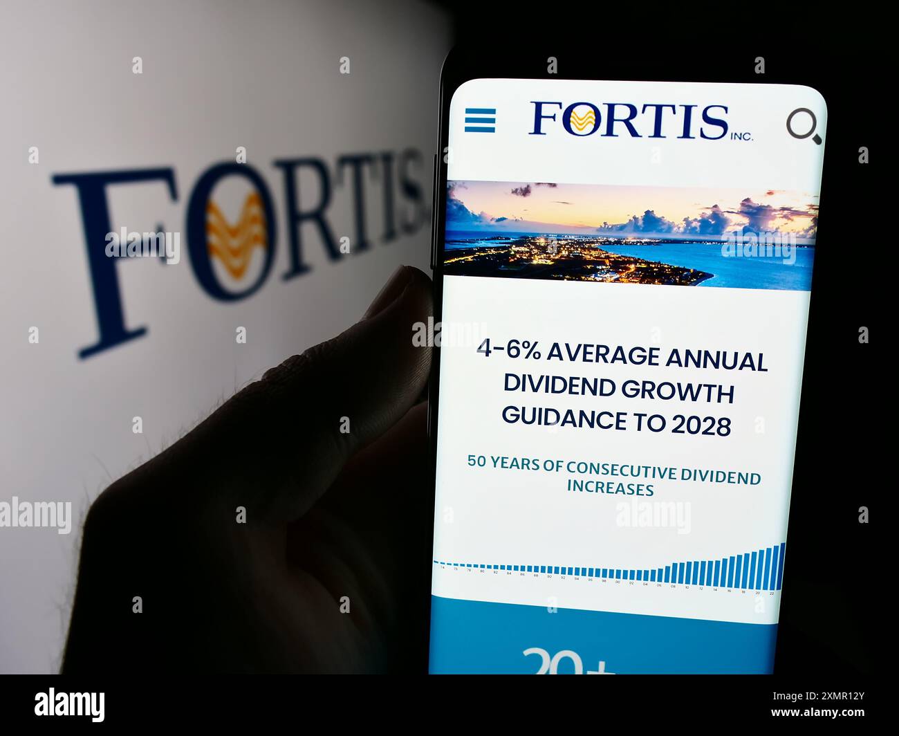 Personne tenant un téléphone cellulaire avec la page Web de la compagnie canadienne de services publics d'électricité Fortis Inc. devant le logo. Concentrez-vous sur le centre de l'écran du téléphone. Banque D'Images