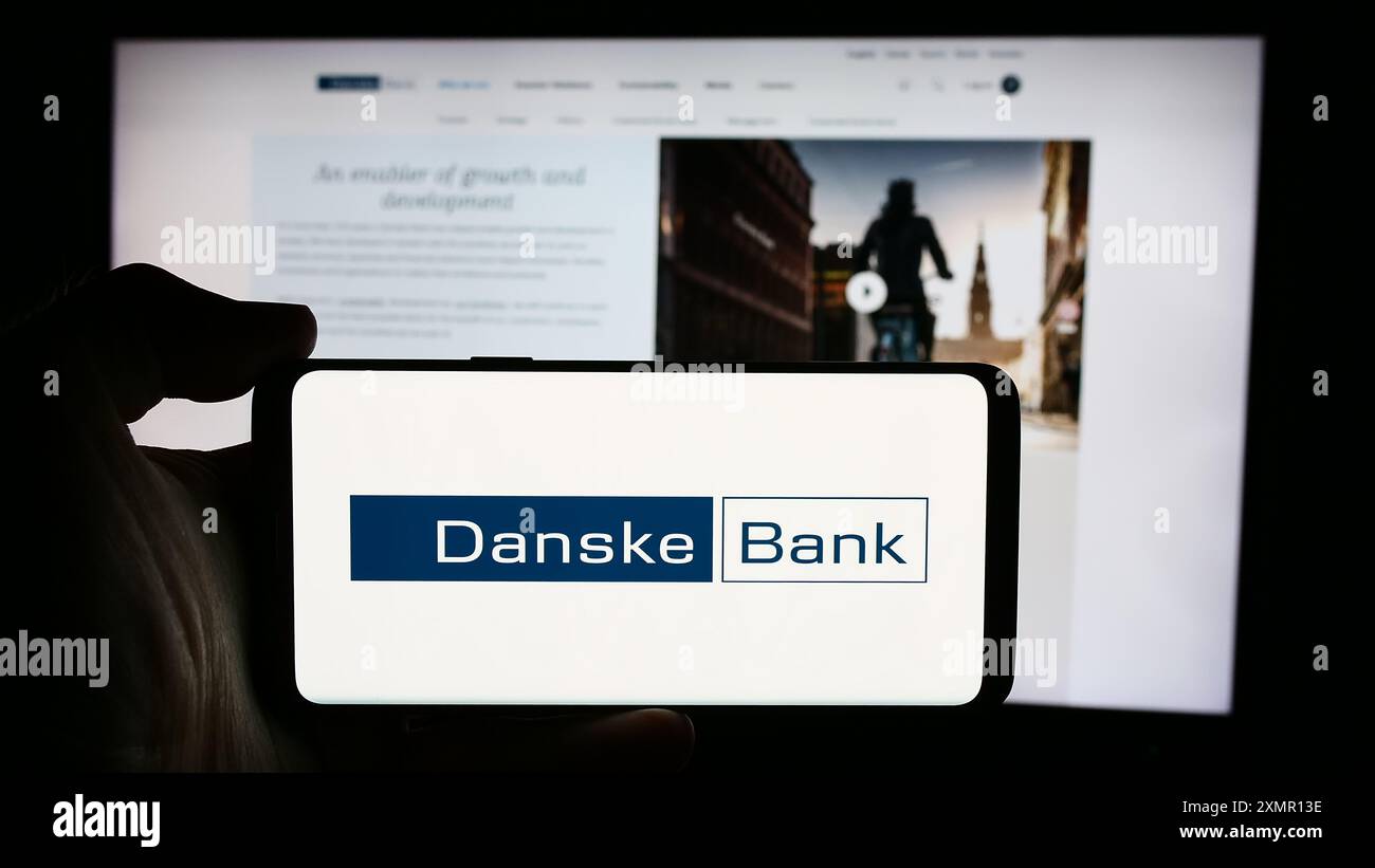 Personne tenant le téléphone portable avec le logo de la société danoise de services financiers Danske Bank COMME en face de la page Web de l'entreprise. Concentrez-vous sur l'affichage du téléphone. Banque D'Images