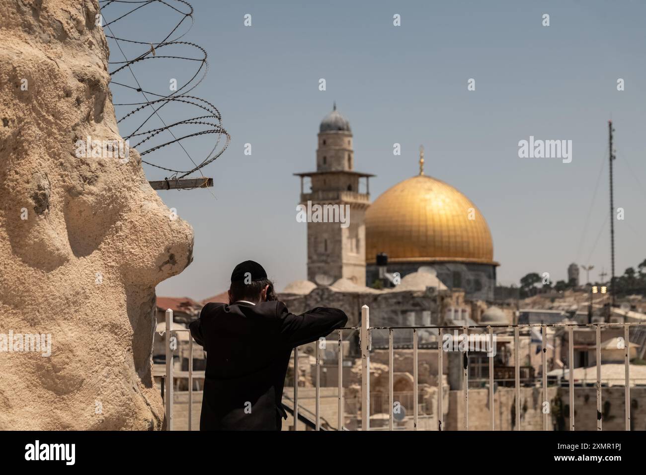 Un adorateur juif regarde le Dôme du Rocher et le mur occidental depuis une terrasse de la vieille ville. Le mur occidental, également connu sous le nom de mur des lamentations à l'Ouest et mur d'Al Buraq dans l'Islam, est une destination de pèlerinage pour les croyants juifs. Situé dans la vieille ville de Jérusalem, il fait partie du mur de soutènement du Mont du Temple. Une cloison métallique divise la zone en deux : les hommes à gauche et les femmes à droite. Tout au long de la journée, les croyants juifs visitent le site pour prier, lire les livres sacrés de la Torah et laisser une note de papier à l’intérieur des fissures du mur. Toute la zone est surveillée par ISR Banque D'Images