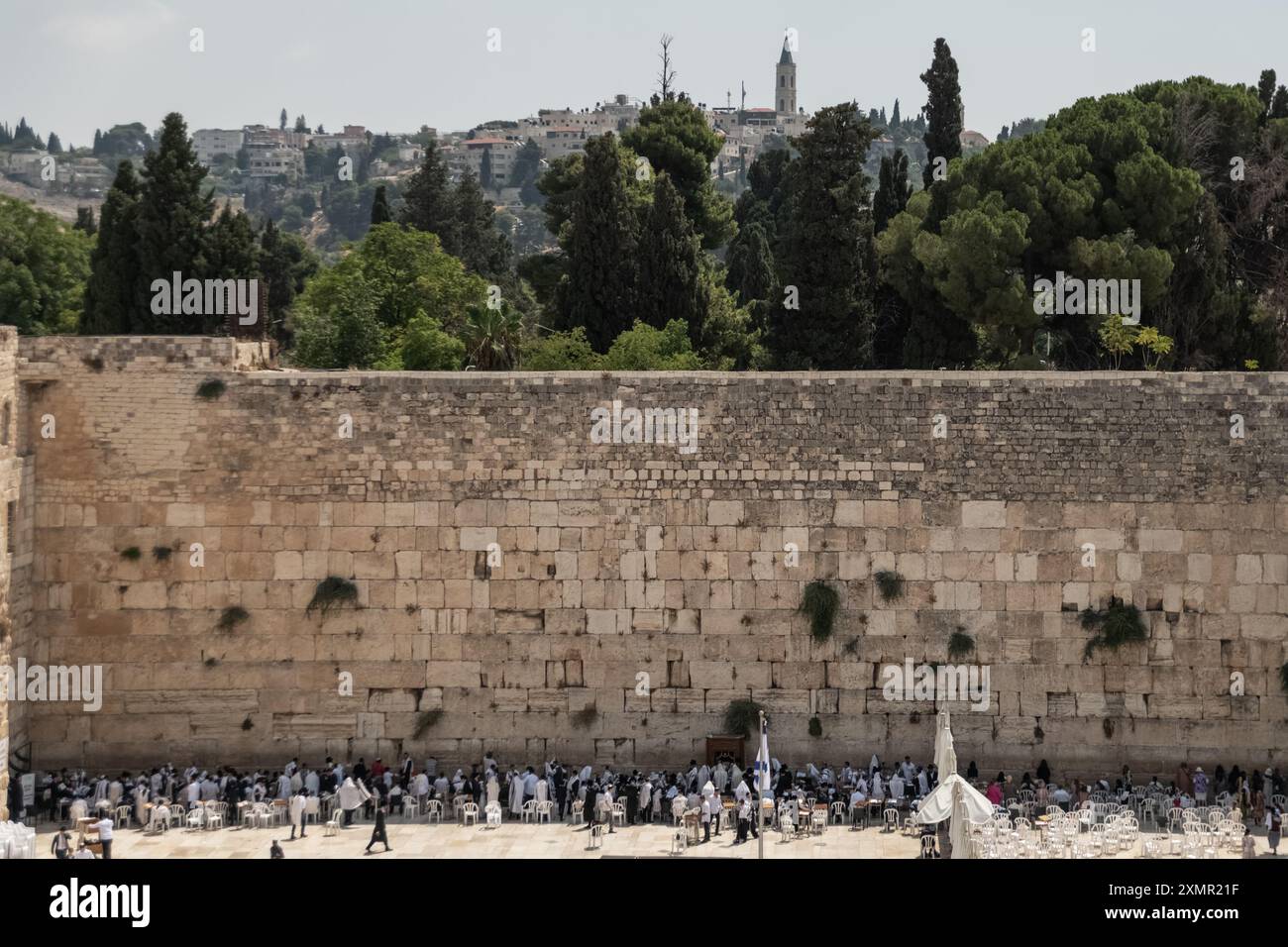 Les fidèles juifs prient du côté des hommes du mur occidental. Le mur occidental, également connu sous le nom de mur des lamentations à l'Ouest et mur d'Al Buraq dans l'Islam, est une destination de pèlerinage pour les croyants juifs. Situé dans la vieille ville de Jérusalem, il fait partie du mur de soutènement du Mont du Temple. Une cloison métallique divise la zone en deux : les hommes à gauche et les femmes à droite. Tout au long de la journée, les croyants juifs visitent le site pour prier, lire les livres sacrés de la Torah et laisser une note de papier à l’intérieur des fissures du mur. Toute la zone est surveillée par des soldats israéliens. Banque D'Images