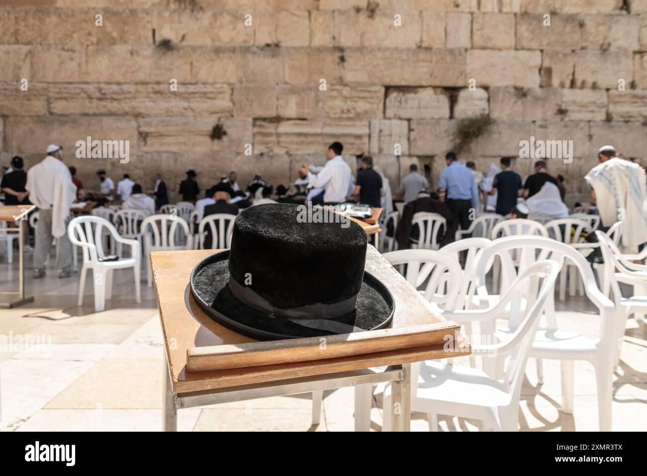 26 juillet 2024, Jérusalem, Israël : un chapeau juif orthodoxe traditionnel laissé sur un bureau pendant que des fidèles juifs prient du côté des hommes du mur Occidental. Le mur occidental, également connu sous le nom de mur des lamentations à l'Ouest et mur d'Al Buraq dans l'Islam, est une destination de pèlerinage pour les croyants juifs. Situé dans la vieille ville de Jérusalem, il fait partie du mur de soutènement du Mont du Temple. Une cloison métallique divise la zone en deux : les hommes à gauche et les femmes à droite. Tout au long de la journée, les croyants juifs visitent le site pour prier, lire les livres sacrés de la Torah et laisser une note de papier à l'intérieur des fissures du mur Banque D'Images