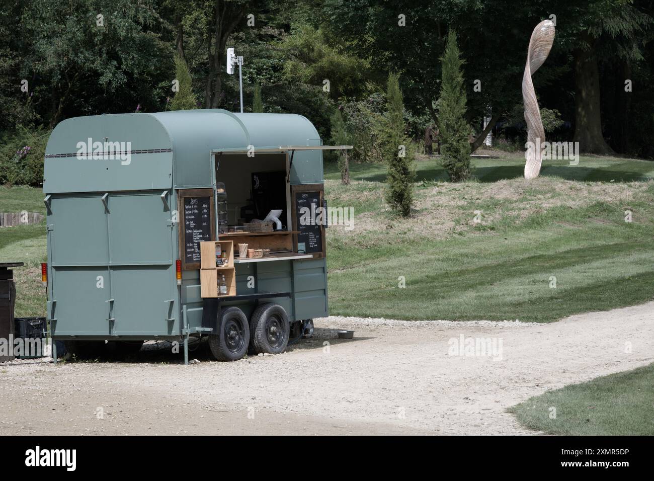 Un kiosque de nourriture fabriqué à partir d'une boîte à chevaux convertie dans le jardin Himalayan & sculpture Park avec une œuvre d'art (Samara) en arrière-plan Banque D'Images