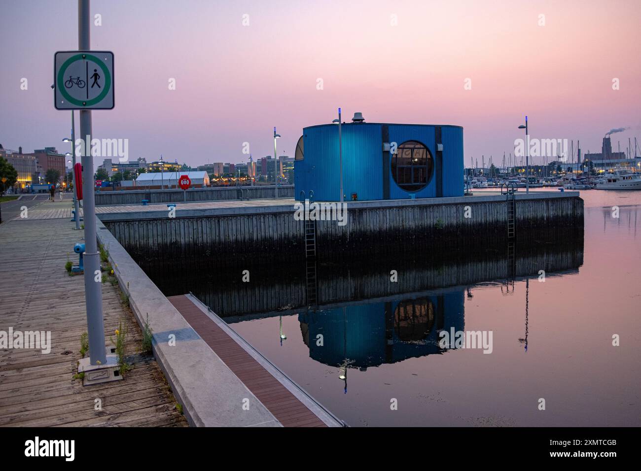 Québec, Canada - 18 juillet 2023 : un petit bâtiment bleu dans le vieux port de Québec au crépuscule avec un peu d'éclairage et quelques personnes méconnaissables dedans Banque D'Images