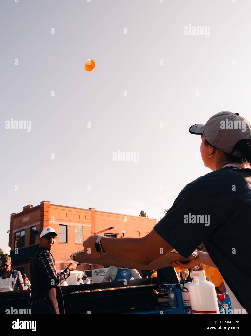Une bénévole tente d'attraper une crêpe sur son plateau pendant le déjeuner de crêpes Cheyenne Frontier Days à Cheyenne, Wyoming, le 26 juillet 2024. Le petit-déjeuner aux crêpes Cheyenne Frontier Days est une tradition de longue date qui se tient pendant les Cheyenne Frontier Days annuels. Il propose des crêpes gratuites au public et est l'un des moments forts de ce festival de 10 jours. Des bénévoles des organisations locales et du personnel militaire américain aident à préparer et à servir le petit déjeuner à des milliers de participants. Le petit déjeuner se compose généralement de crêpes, jambon, café et lait, créant un sentiment de communauté et célébrant le spir occidental Banque D'Images