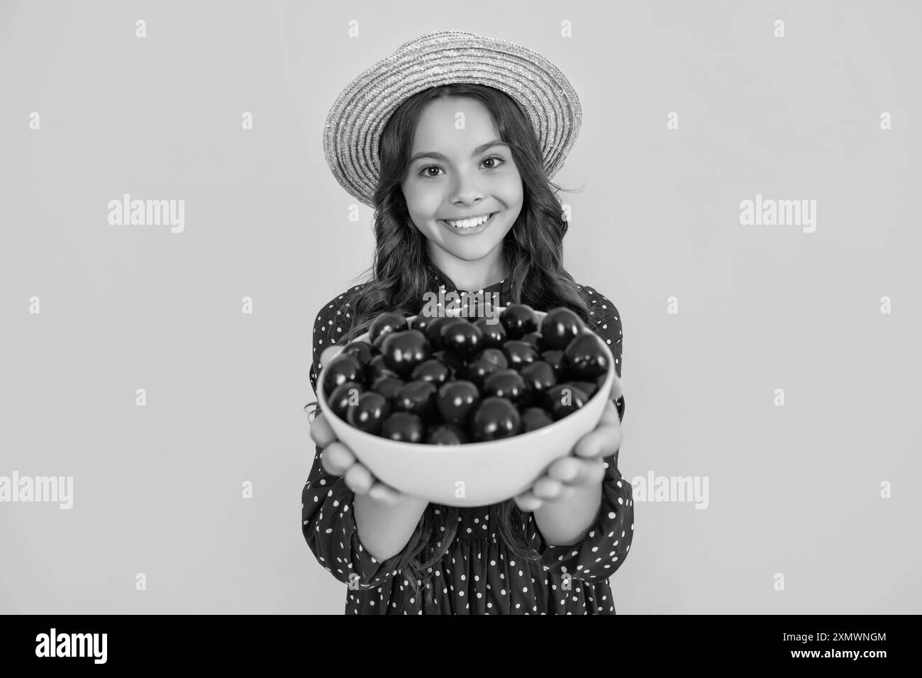 foyer sélectif de bol de cerise dans les mains de l'enfant heureux de l'adolescence sur fond jaune Banque D'Images
