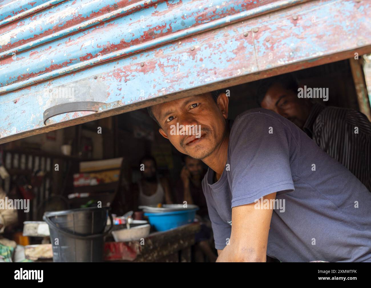 Homme bangladais regardant sous un rideau de fer, Division de Dhaka, Dhaka, Bangladesh Banque D'Images