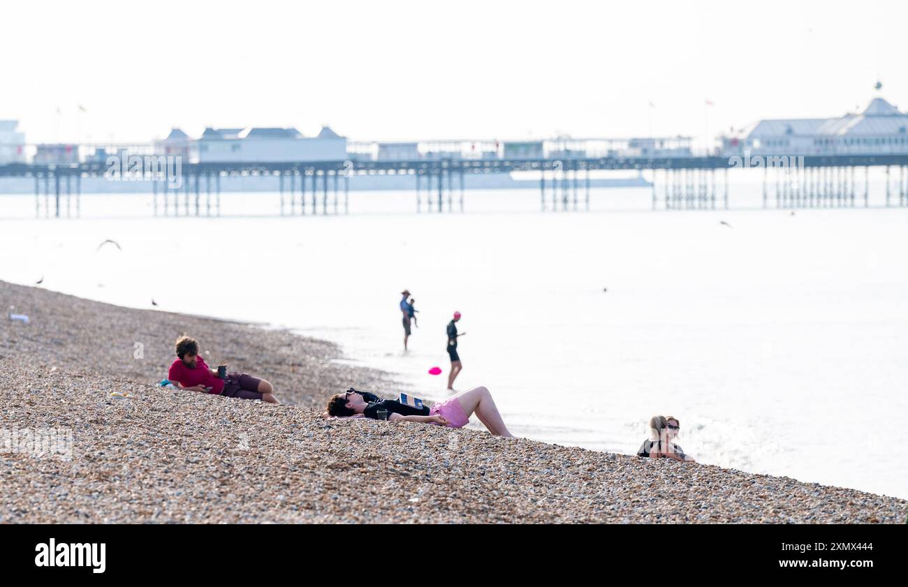 Brighton Royaume-Uni 30 juillet 2024 - tôt le matin, les visiteurs sur Brighton Beach apprécient le soleil chaud car aujourd'hui est prévu pour être le jour le plus chaud de l'année jusqu'à présent avec des températures atteignant plus de 30 degrés dans certaines parties du Sud-est : crédit Simon Dack / Alamy Live News Banque D'Images