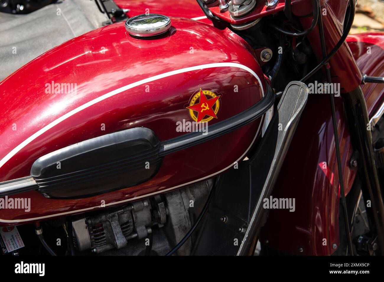 Vue rapprochée d'une moto URAL rouge vintage montrant son emblème et ses détails, mettant en évidence son design classique et ses composants mécaniques. Banque D'Images
