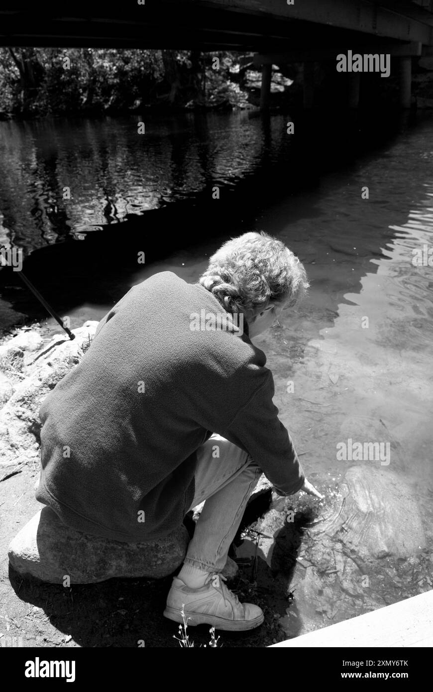 Un moment de sérénité en tant que femme caucasienne, âgée de 50 à 55 ans, qui plonge la main dans le ruisseau au terrain de camping Davidson River, près de Brevard, NC. ÉTATS-UNIS Banque D'Images