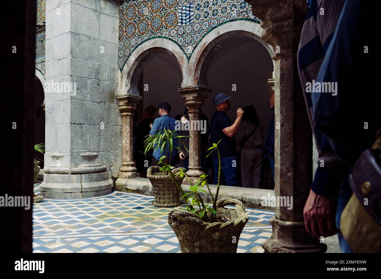 Les visiteurs explorent les arches ornées et les cornières vibrantes de l'une des cours intérieures du palais de Pena Banque D'Images