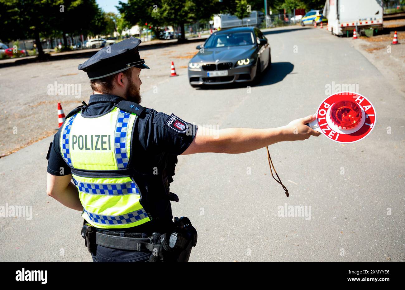 Hambourg, Allemagne. 30 juillet 2024. S'IL VOUS PLAÎT PIX LE SIGNE D'IDENTIFICATION - Un policier arrête une voiture lors d'un contrôle pour des défauts techniques dans le district de Bahrenfeld. Lors d'un contrôle à grande échelle, la police a vérifié le respect des règles de sécurité routière. Crédit : Daniel Bockwoldt/dpa - ATTENTION : les plaques d'immatriculation ont été pixelisées pour des raisons légales/dpa/Alamy Live News Banque D'Images