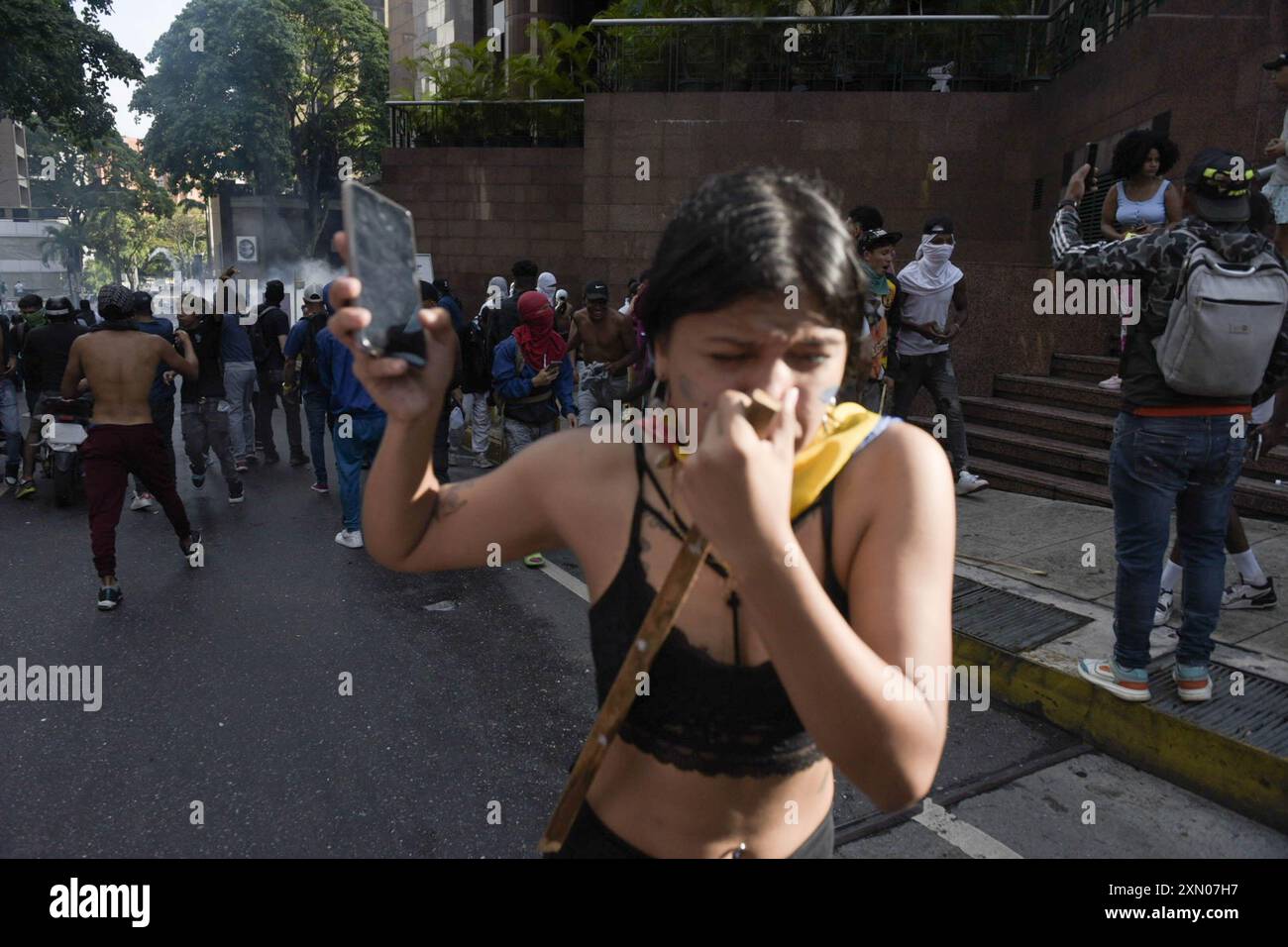 Une femme s'enfuit des gaz lacrymogènes tirés par la Garde nationale vénézuélienne pendant la manifestation. Des centaines de personnes sont descendues dans la rue pour protester dans l'après-midi du 29 juillet, après que le Conseil électoral national (CNE) ait annoncé la veille que le candidat vénézuélien et président Nicolás Maduro était le « vainqueur irréversible ». Le rassemblement a commencé dans l'un des quartiers les plus emblématiques de la ville, 'El Petare'. Les chants exprimaient leur insatisfaction à l'égard du résultat. La situation s'est aggravée lorsque la Garde nationale bolivarienne est venue arrêter l'avancée des manifestants. Banque D'Images