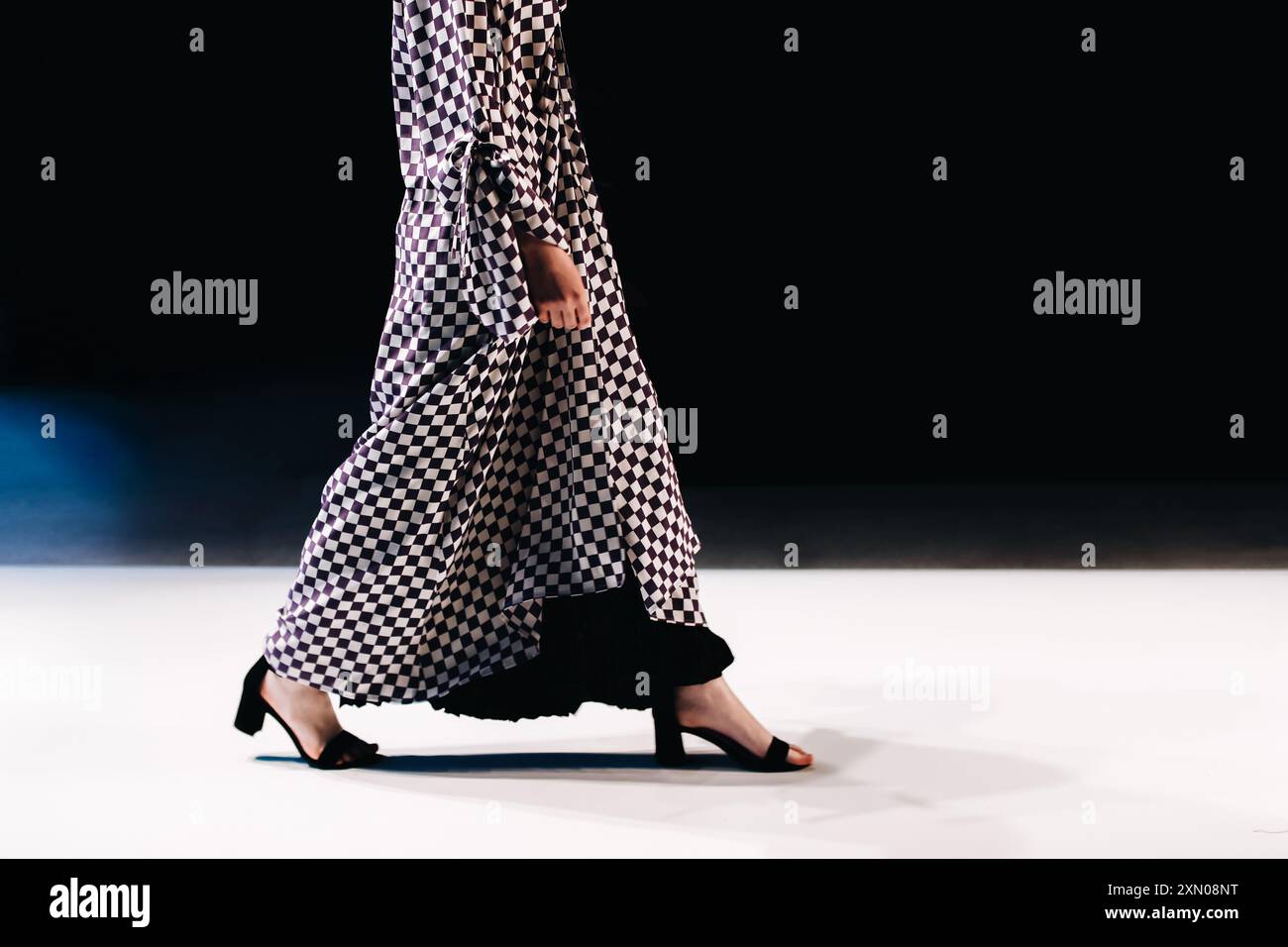 Longue robe noire à carreaux blanche élégante sur figure féminine, détails de mode sur fond noir, espace de copie Banque D'Images