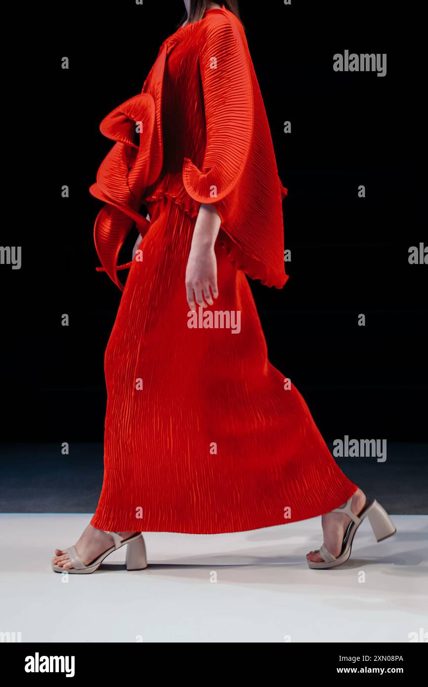 Élégante robe de designer rouge vif sur figure féminine, détails de mode sur fond noir Banque D'Images