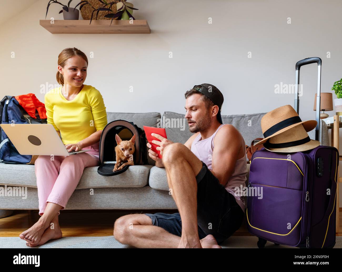 Préparation avant le voyage. Jeune couple réservant le voyage en utilisant l'ordinateur portable et les données des passeports. Banque D'Images