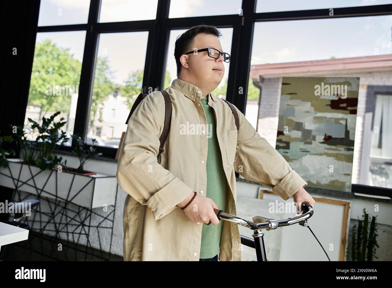 Un jeune homme atteint du syndrome de Down se tient debout avec son vélo, prêt pour une balade. Banque D'Images
