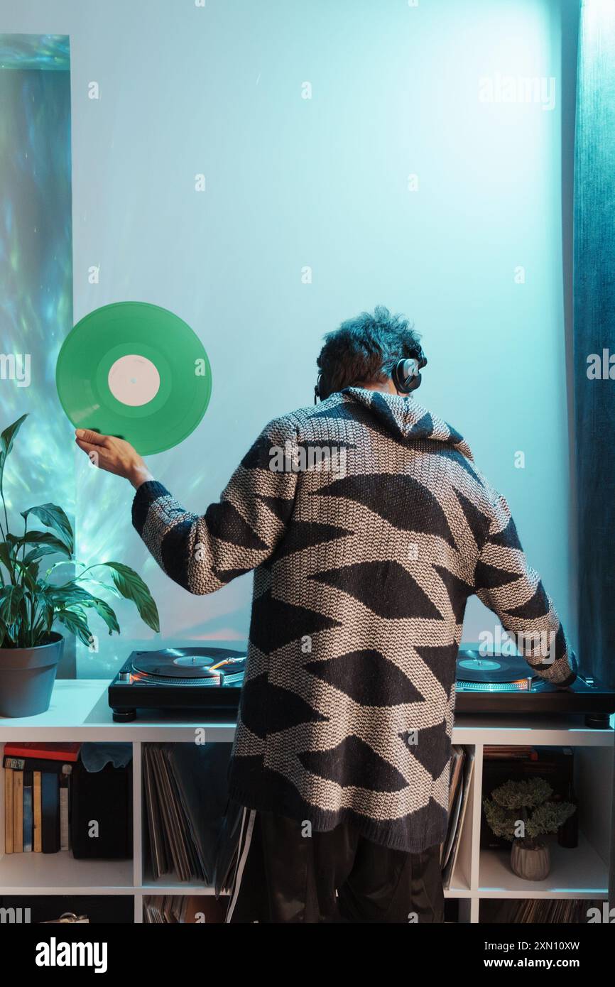 Homme tenant un disque vinyle près de la platine dans une chambre confortable Banque D'Images